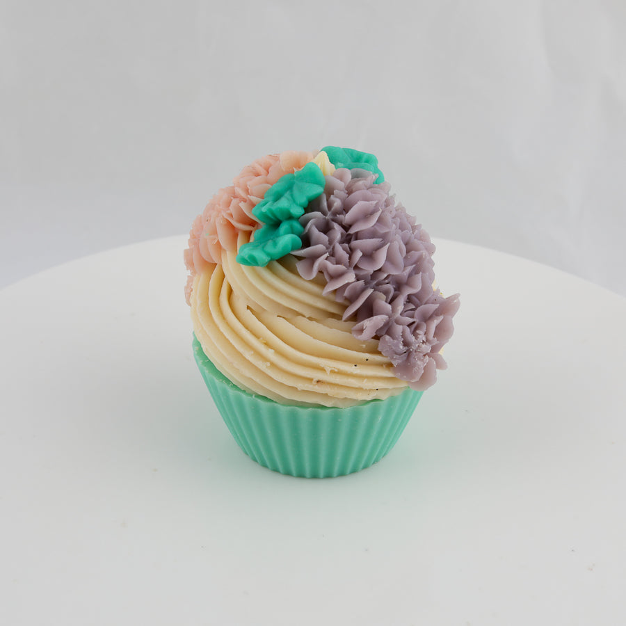 green, yellow, and pink colored cupcake shaped soap with purple lilacs and green leaves on top