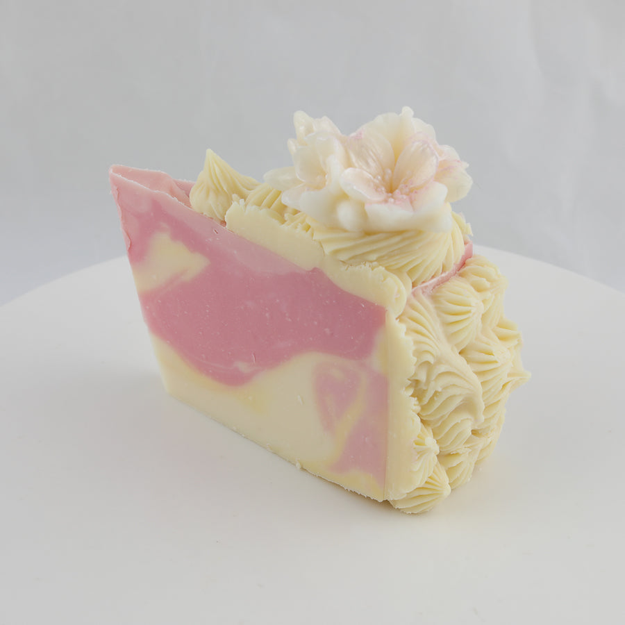 pink and cream colored cake soap with a white sakura flower on top