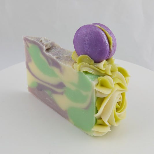 green, purple, cream, and yellow colored cake shaped soap with a purple macaroon on top