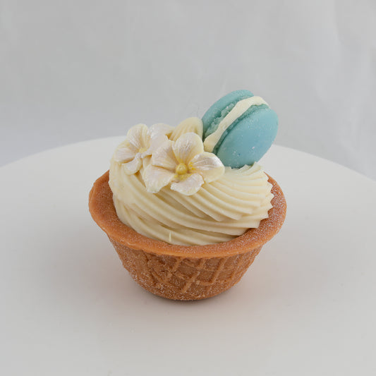 brown and cream colored ice cream waffle cone bowl with white flowers and a blue macaroon on top