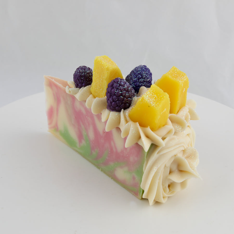 pink, green, and cream colored cake shaped soap with pineapple and blackberries on top