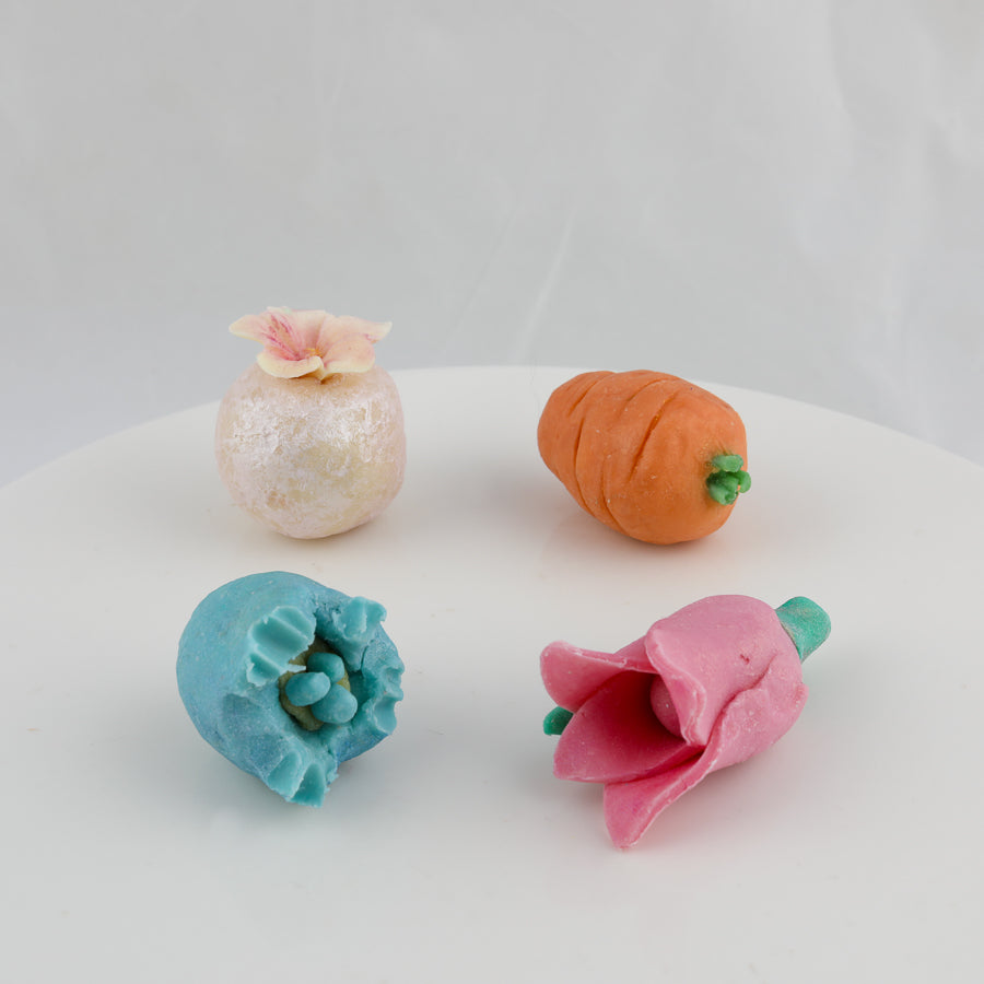 small soaps on the shape of a carrot, rose, pearl with a flower on top, and cracked egg