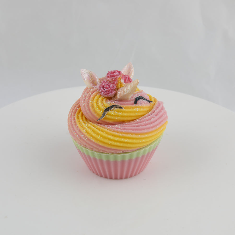 pink, orange, green colored, cupcake shaped soap with a unicorn horn, ears, and eyelashes on top and roses above the horn